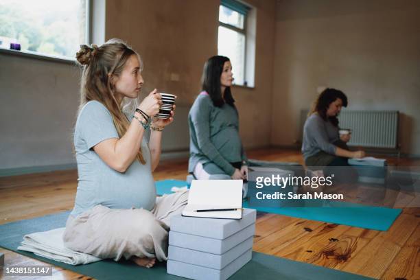pregnant women sat in pre-natal workshop, writing affirmations and drinking tea - prenatal care stockfoto's en -beelden