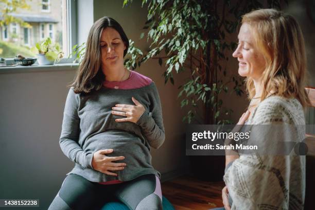 yoga teacher and pregnant woman both sit smiling with eyes closed - beautiful woman 35 sit studio stock-fotos und bilder