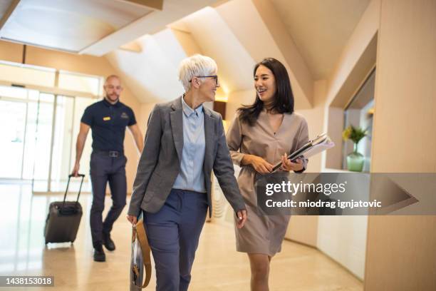 businesswoman entering a hotel with her assistant - entering atmosphere stock pictures, royalty-free photos & images