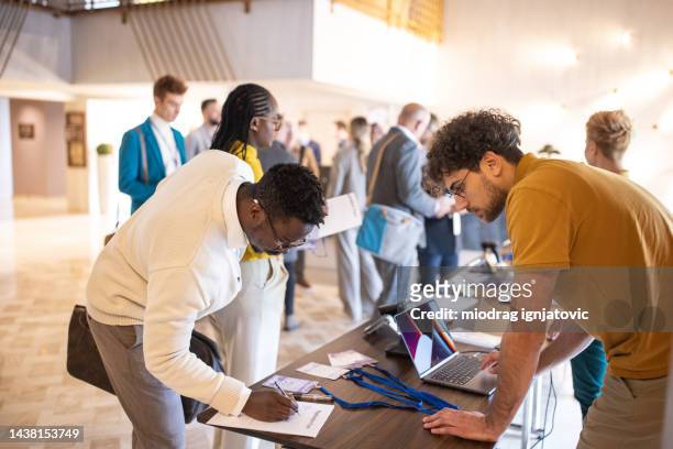 business conference participants registering for a conference in the lobby of a luxury hotel - convention center stock pictures, royalty-free photos & images