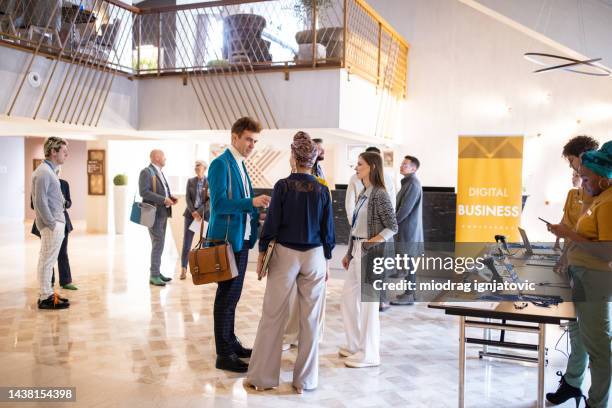 business conference participants socializing in the lobby of a hotel before the conference begins - business networking event stock pictures, royalty-free photos & images