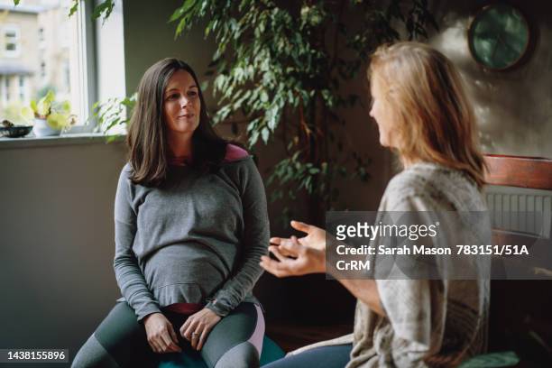 pregnant woman sat listening to yoga teacher - pregnancy class stock-fotos und bilder