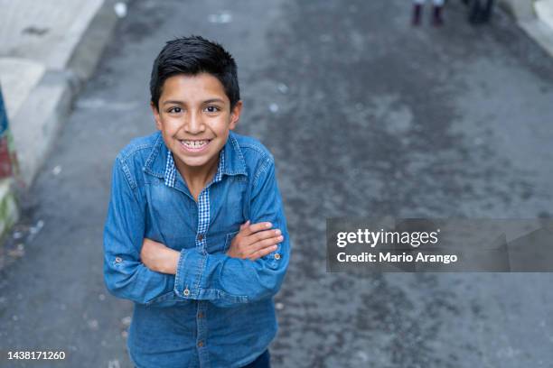 latin boy mit einem durchschnittsalter von 10 jahren ist auf der straße und schaut in die kamera, die ihn porträtiert, während er lächelt - girl 10 years old happy stock-fotos und bilder