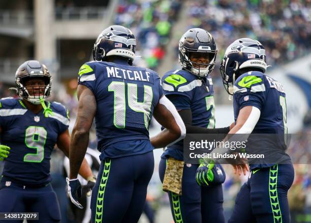 Geno Smith of the Seattle Seahawks greets DK Metcalf and Dee Eskridge after throwing to Metcalf for a touchdown against the New York Giants during...