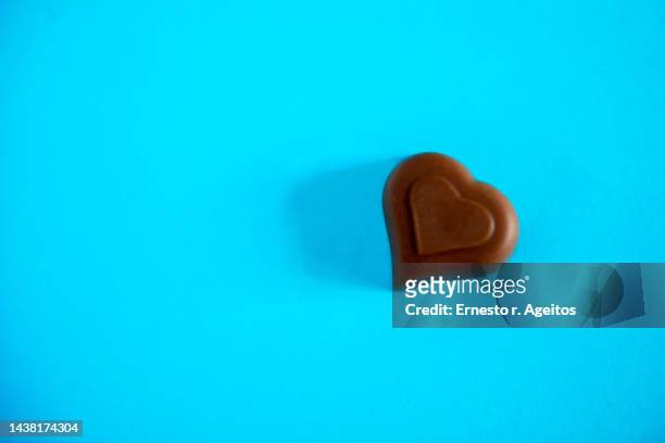 heart shaped chocolate against plaid blue background - chocolate heart stock-fotos und bilder