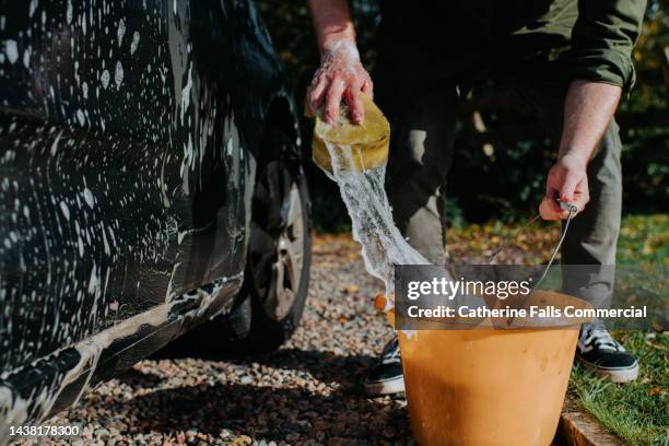 a man hand washes a car with a sponge and bucket - car wash stock pictures, royalty-free photos & images