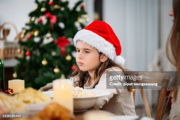 young girl sits bored at the christmas dinner table. - bored housewife stock pictures, royalty-free photos & images