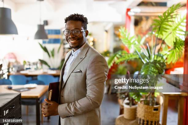 porträt eines schwarzen geschäftsmannes in einem luxusrestaurant - grüner anzug stock-fotos und bilder