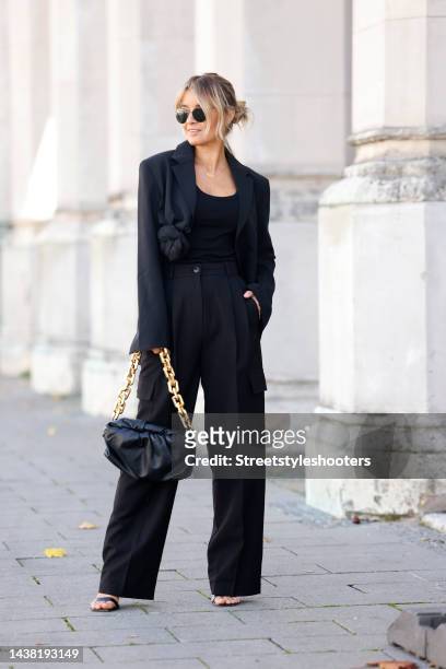 Influencer Gitta Banko wearing a black blazer by Jacquemus, black cargo pants by The Frankie Shop, black high heel sandals by Gianvito Rossi, a black...