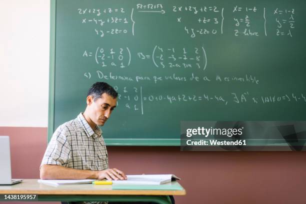 math teacher reading book in classroom - differential focus education stock pictures, royalty-free photos & images