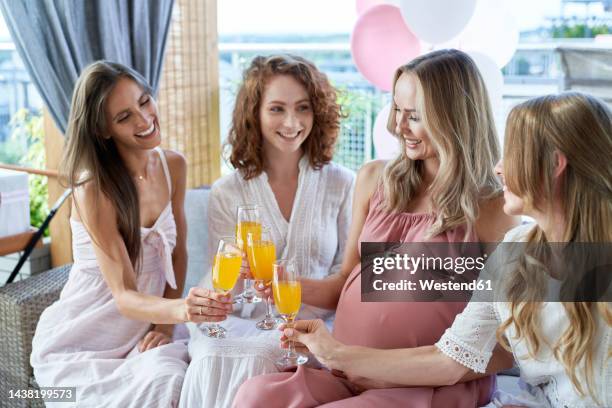 smiling pregnant woman toasting cocktail glasses with friends - 4 cocktails stockfoto's en -beelden