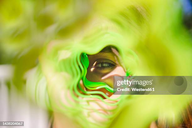 woman looking through green metal coil toy - metal coil toy stockfoto's en -beelden