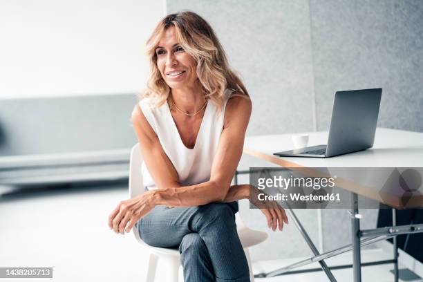 businesswoman sitting with legs crossed on chair at office - legs crossed at knee stock pictures, royalty-free photos & images