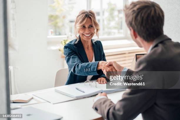 happy businesswoman doing handshake with man at office - colloquio di lavoro foto e immagini stock