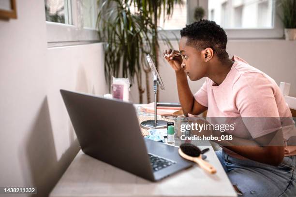 woman using tweezers for her eyebrows while looking in the mirror - eyebrow tweezers stock pictures, royalty-free photos & images