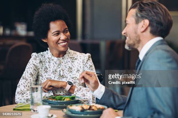 couple of smiling business persons eating together in a restaurant - affluent dining stock pictures, royalty-free photos & images