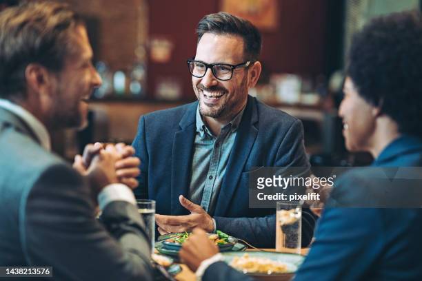 smiling businessman talking to his coworkers during a dinner - white dinner jacket stock pictures, royalty-free photos & images