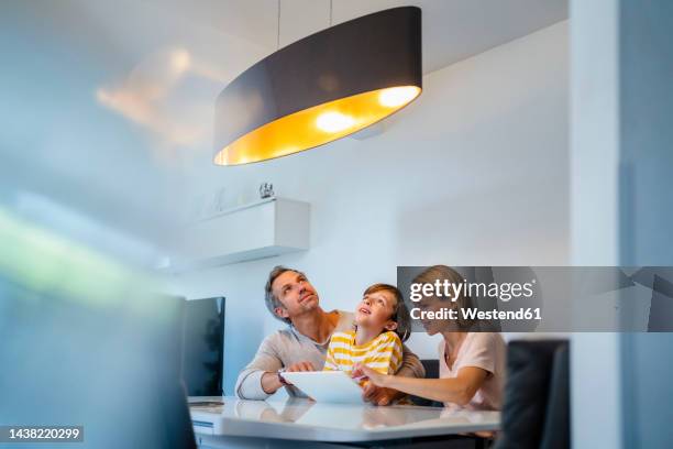 family controlling ceiling lamp with tablet pc in smart home - connected home stock-fotos und bilder