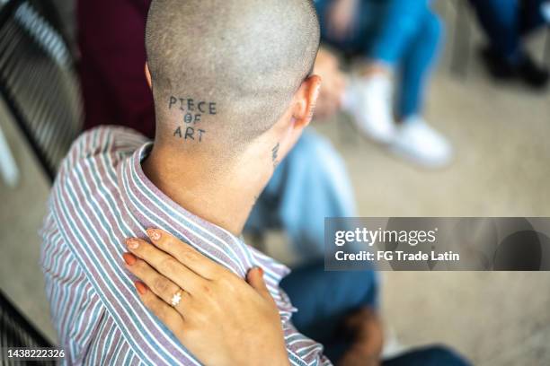 nahaufnahme einer hand auf schulter bei einer gruppentherapie - tattoo shoulder stock-fotos und bilder
