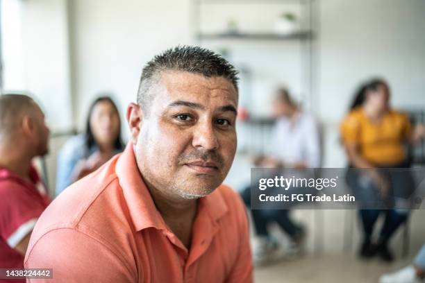 portrait of mid adult man during a group therapy at mental health center - male volunteer stockfoto's en -beelden