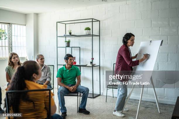 mid adult woman doing a presentation during a meeting - market research stock pictures, royalty-free photos & images