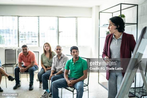 mid adult woman doing a presentation during a meeting - employee welfare stockfoto's en -beelden