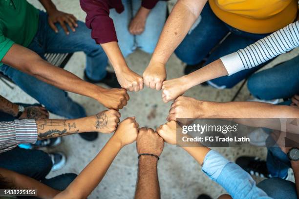 close-up of a team doing fist bump - team hands in huddle stock pictures, royalty-free photos & images