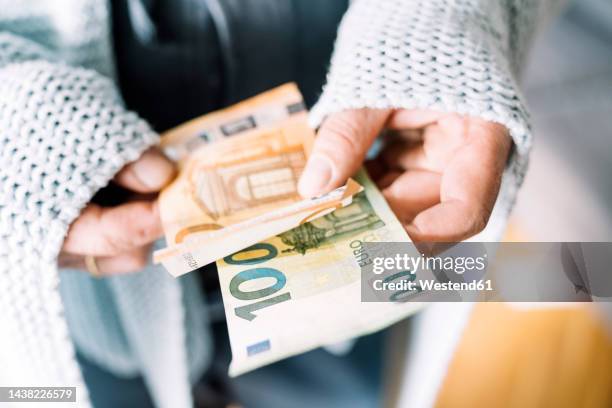 hands of man wrapped in blanket holding euro notes - geldschein stock-fotos und bilder