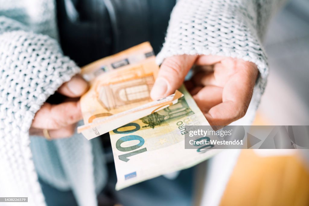 Hands of man wrapped in blanket holding Euro notes