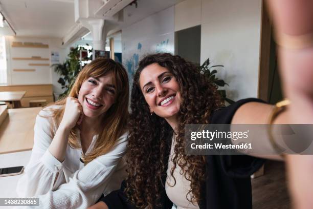 two happy businesswomen taking a selfie in office - selfi stock-fotos und bilder