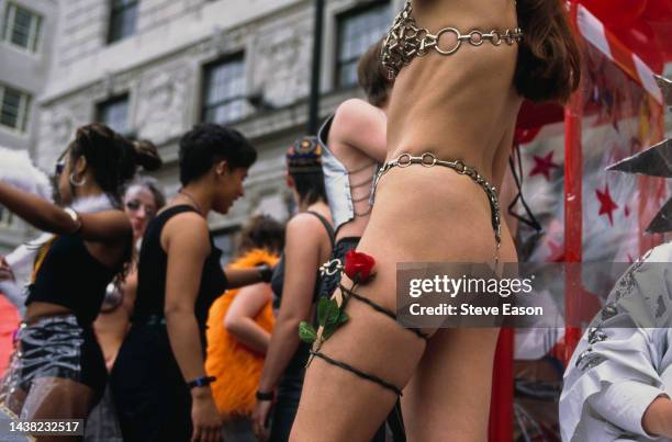 Young woman in a metallic chain bikini with a red rose strapped to their thigh on a float at the Lesbian and Gay Pride event, London, 24th June 1995....