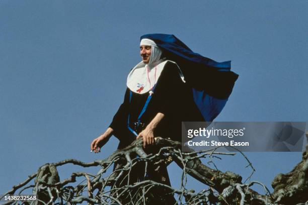 Marcher dressed as a nun enjoys a cigarette while standing in a tree during the Lesbian and Gay Pride event, London, 24th June 1995.
