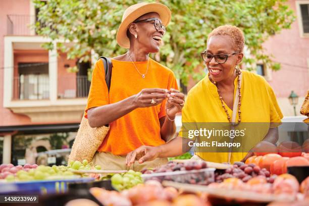 two mature women shopping together at an outdoor food market - mercato di prodotti agricoli foto e immagini stock