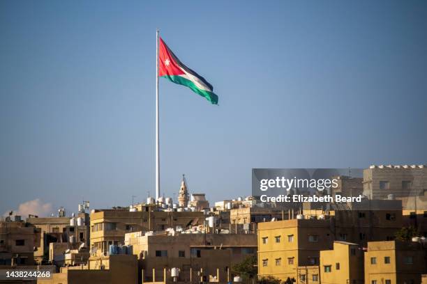 the jordanian flag flies over the hills of amman - amman jordan stock pictures, royalty-free photos & images