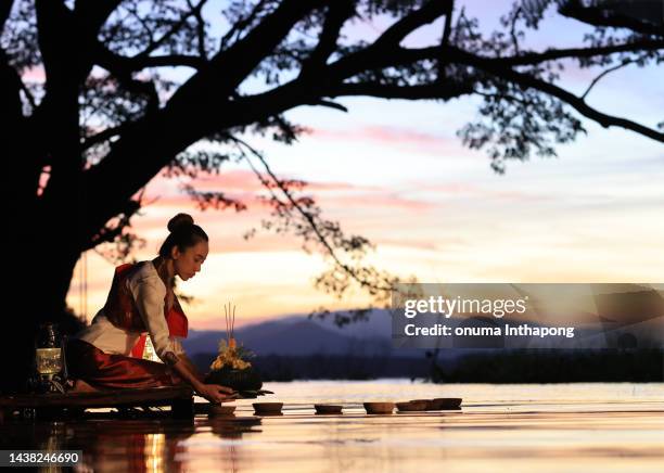 young woman hold and lift krathong up to head to pray respect the river goddess , loy krathong festivals at thailand for goddess of water full moon night in november, loi krathong festival - loi krathong stockfoto's en -beelden