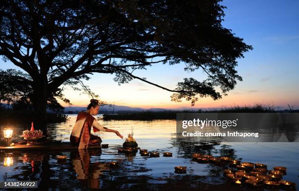 asia woman in thai dress traditional hold kratong and bring krathong to float in loi kratong day of thailand. loi krathong traditional festival held every november to pray respect to water goddess - heritage month stock pictures, royalty-free photos & images