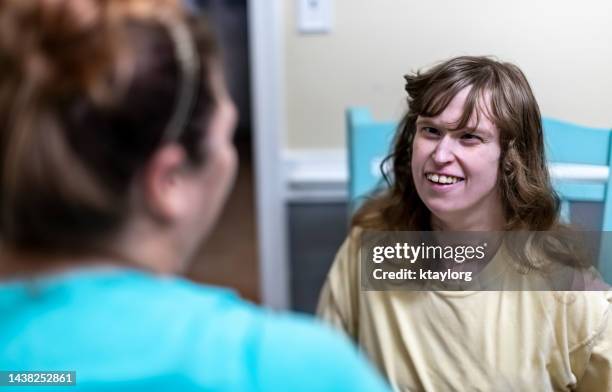 caregiver brings a smile to intellectually disabled woman's face - mental disability stock pictures, royalty-free photos & images