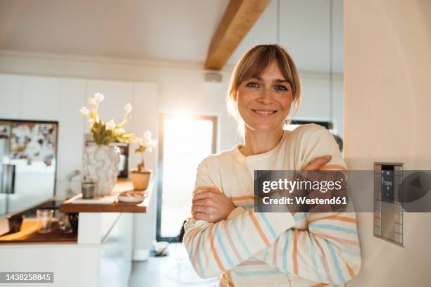 happy woman hugging self near thermostat on wall at home - heating home stock pictures, royalty-free photos & images