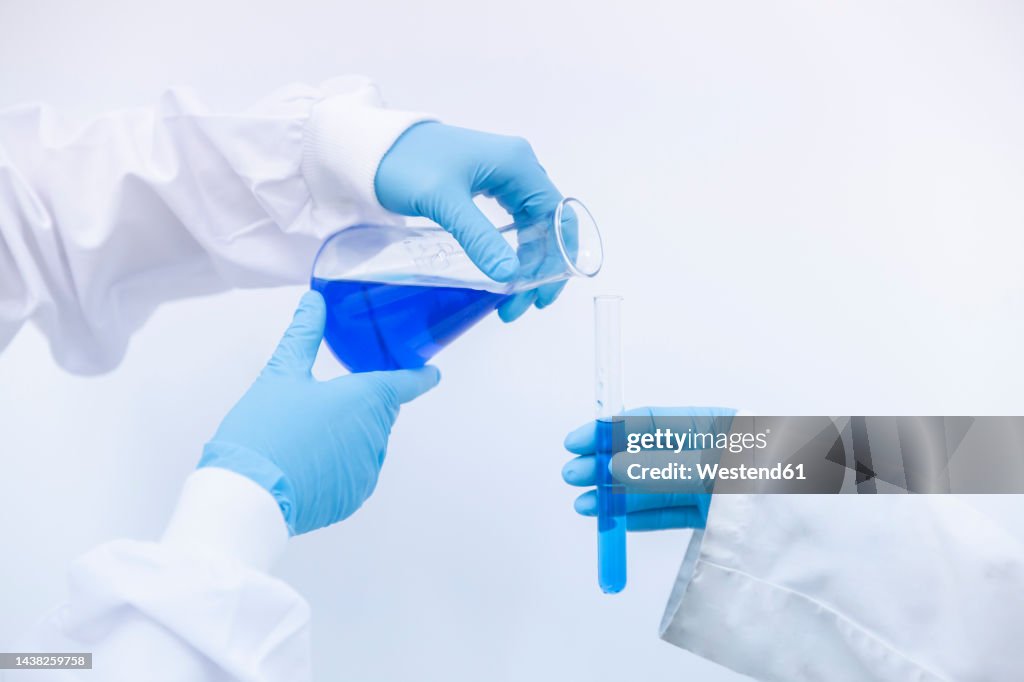 Scientist pouring blue liquid in test tube at laboratory