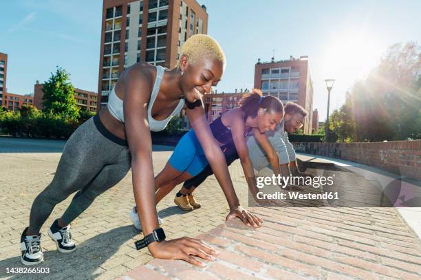 smiling sports people doing push-ups on wall - bodyweight training stock pictures, royalty-free photos & images