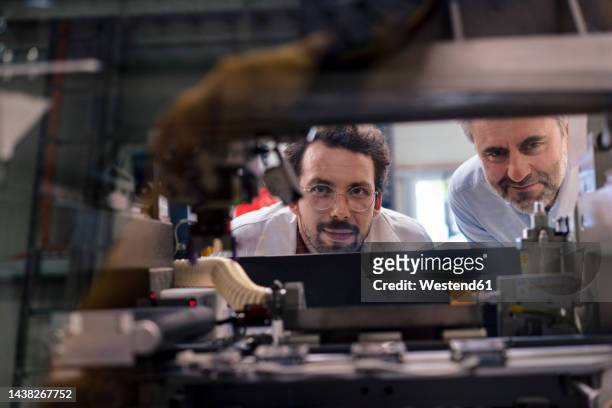 mature businessman with colleague examining machinery at industry - 3d printen factory stockfoto's en -beelden