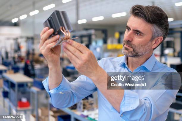 businessman examining machine part in industry - halbleiter stock-fotos und bilder