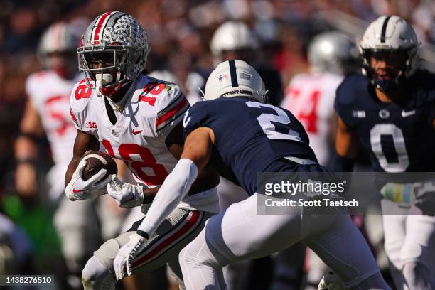 Marvin Harrison Jr. #18 of the Ohio State Buckeyes carries the ball as Keaton Ellis of the Penn State Nittany Lions defends during the first half at...