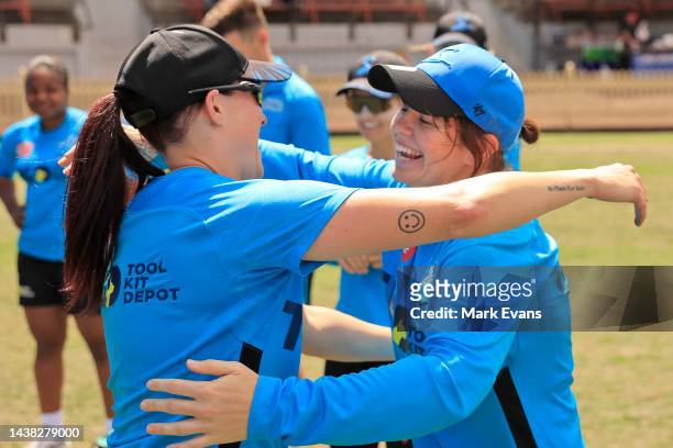 Tegan McPharlin of the Strikers , is hugged by Megan Schutt of the Strikers after receiving her cap for 100 games during the Women's Big Bash League...