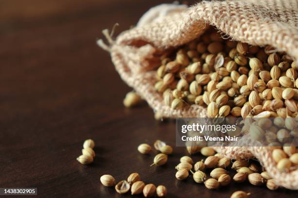 close-up of coriander seeds in a jute bag on a wooden table - koriander stockfoto's en -beelden