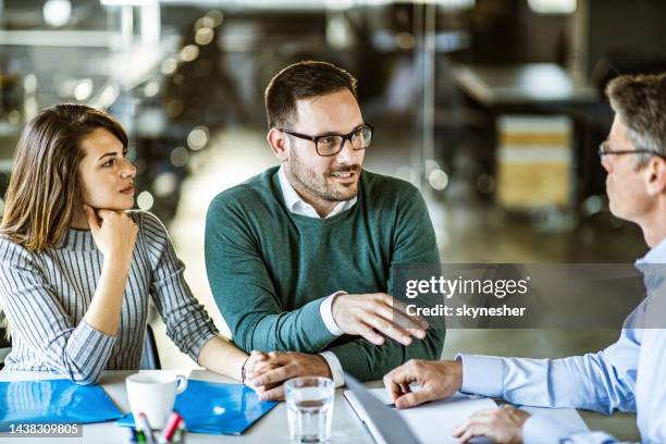 young couple talking to real estate agent on a meeting in the office. - real estate office stockfoto's en -beelden