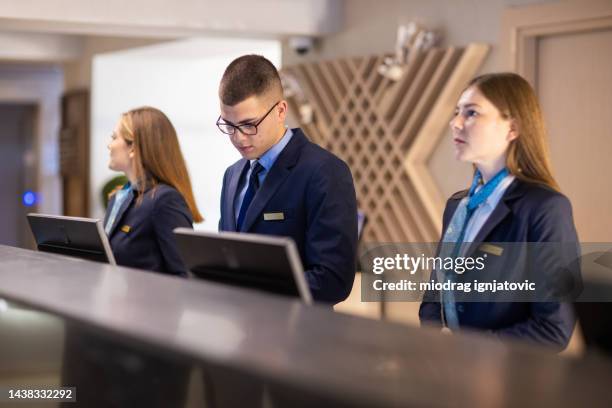 hotel receptionists at a reception desk in a luxury hotel - hotel occupation stock pictures, royalty-free photos & images