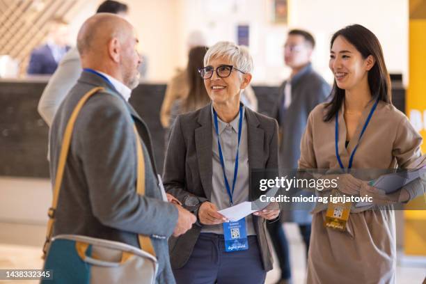 gens d’affaires socialisant dans le hall d’un hôtel avant le début d’une conférence - lanière objet manufacturé photos et images de collection