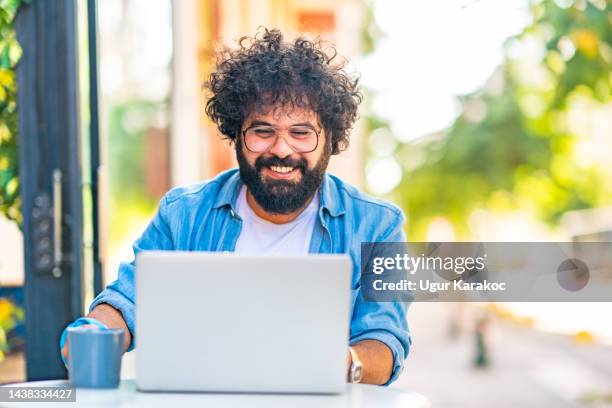 man using laptop at coffee shop, smiling - mid adult stockfoto's en -beelden