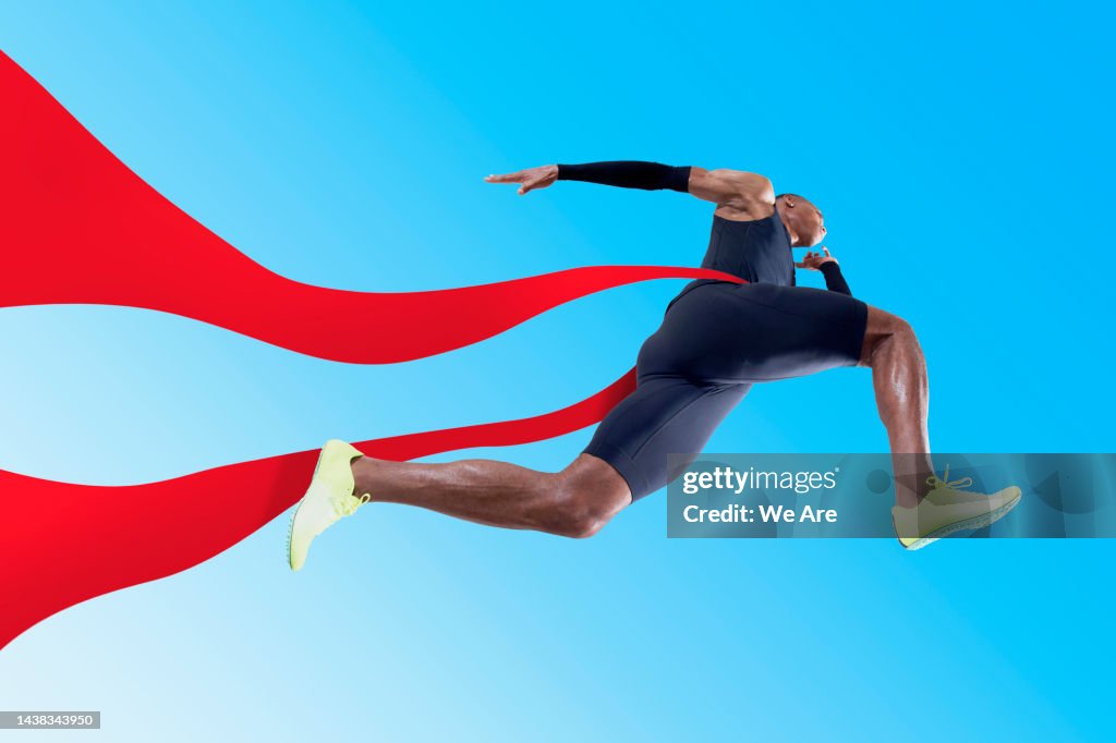 Athlete running through red ribbon